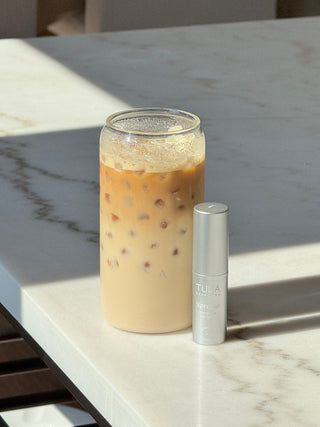 TULA 'Spresso Energizing Eye Balm in Ice in front of a glass of iced coffee