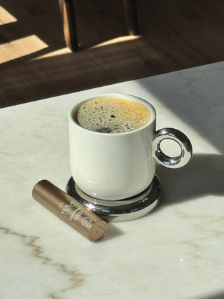 TULA 'Spresso Energizing Eye Balm in Americano next to a cup of coffee