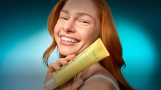 Woman holding a yellow Tula product against a blue gradient background