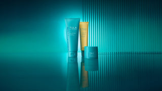 Three Tula skincare products on a reflective surface with a teal gradient background