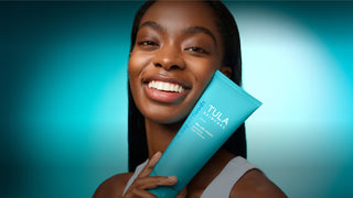 Woman holding a Tula product against a blue gradient background