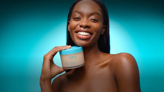 Woman holding a Tula product against a blue gradient background