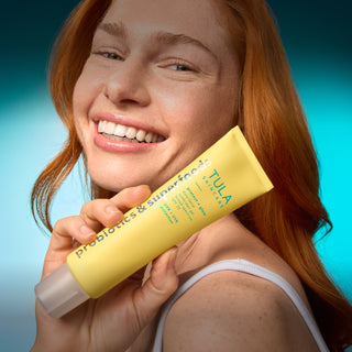 Woman holding a yellow Tula product against a blue gradient background