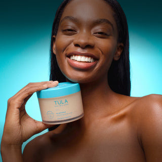 Woman holding a Tula product against a blue gradient background