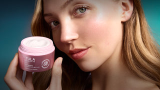 Woman holding a pink Tula product against a gradient background