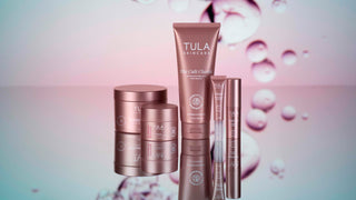 Tula skincare products on a reflective surface with a blurred background