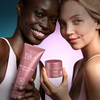 Two women holding Tula skincare products against a gradient background