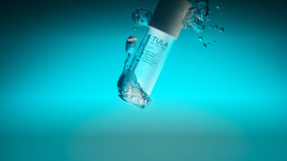Tula skincare bottle with water droplets on a blue gradient background
