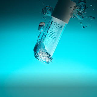 Tula skincare product being submerged in water with a blue gradient background