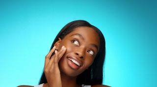 Model touching face with blue background