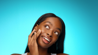 Woman touching her face against a blue background
