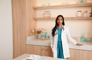 Doctor in white coat in office with products on counter. 