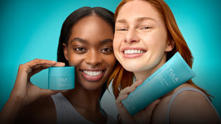 Two women holding Tula skincare products against a teal background