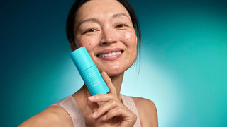 Woman holding product in front of blue background
