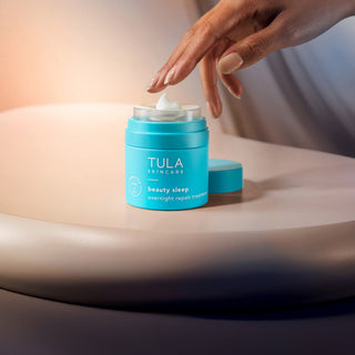 TULA beauty sleep uncapped with product dollop. Hand reaching out to touch. 