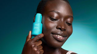 Woman holding a blue Tula product against a gradient background