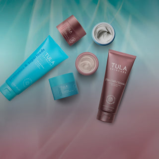 A flat-lay arrangement of Tula Skincare products on a soft teal gradient background.
