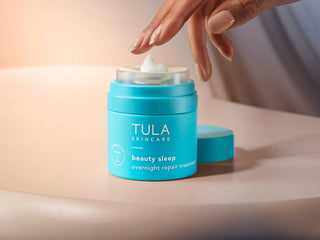 TULA beauty sleep uncapped with product dollop. Hand reaching out to touch. 