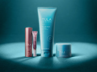 TULA Skincare Products Under a Heart-Shaped Spotlight on Blue Background