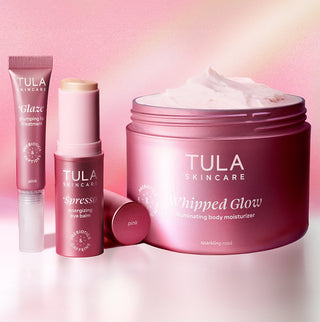 Tula Skincare products including a jar, stick, and bottle on a pink background