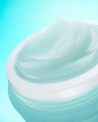Close-up of a light blue cream jar with a smooth texture on a gradient background
