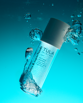 Tula skincare bottle with water droplets on a blue background