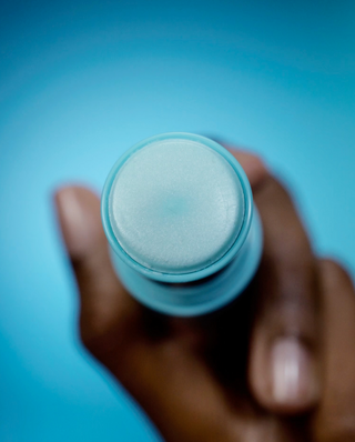 Hand holding a blue container against a blue background