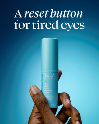 Tula skincare product held by a hand with a blue background and text 'A reset button for tired eyes'.