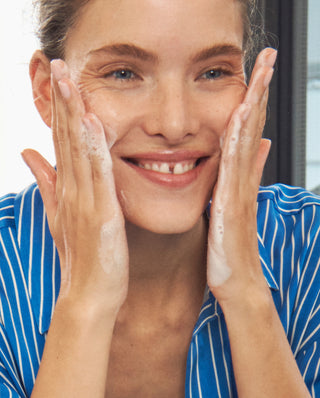 Woman applying cream to her face with a blurred background