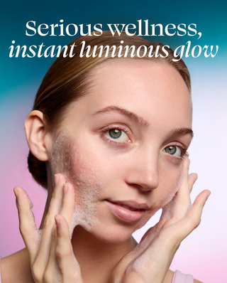 Woman applying a skincare product with text 'Serious wellness, instant luminous glow' on a gradient background.