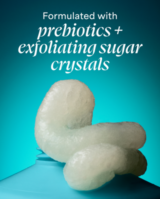 White exfoliating sugar crystals on a blue background with text about prebiotics and exfoliating sugar crystals.