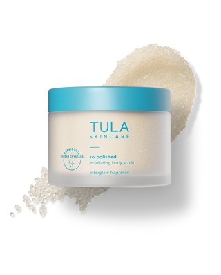 Tula Skincare jar with a scoop of body scrub on a white background