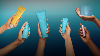 Hands holding various Tula skincare products against a gradient blue background
