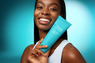 Woman holding a Tula product against a blue background