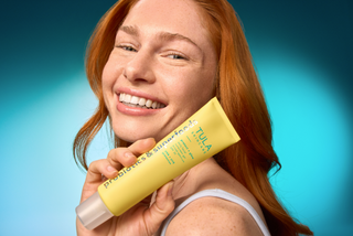 Woman holding a Tula product against a blue gradient background