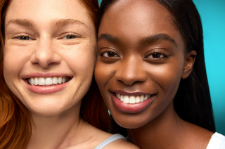 Two women with smiling faces against a teal background