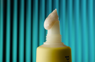 Close up of SPF dispensing from tube with blue background.