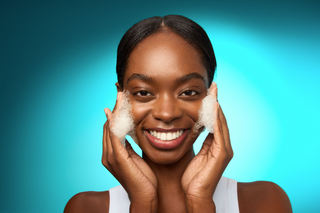 Model applying cleanser with blue background