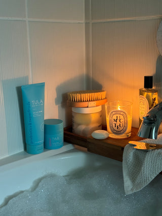 Bathroom scene with bath products including bottles and a brush on a tiled surface.